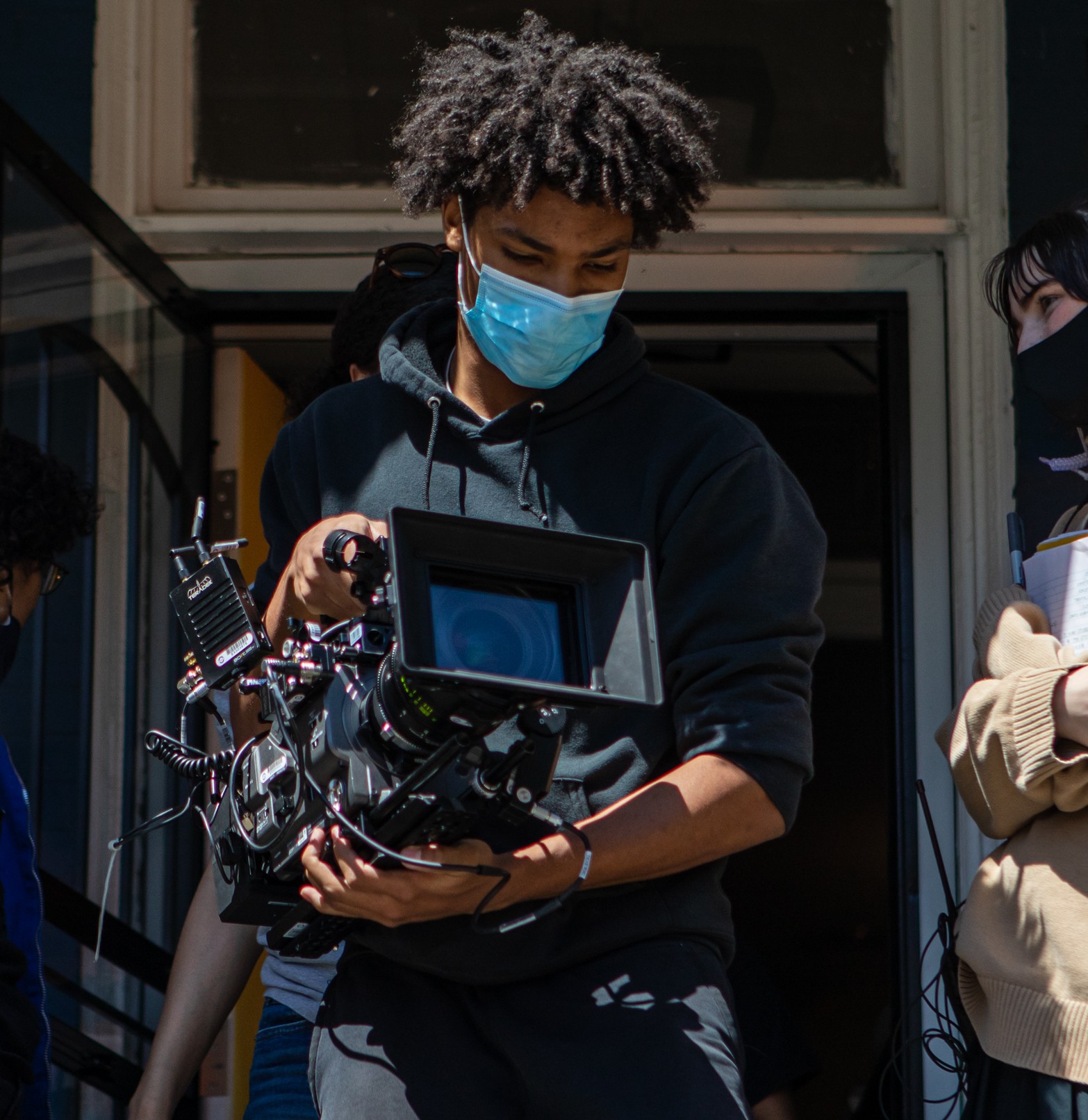 A Black person is on a film set holding a camera.