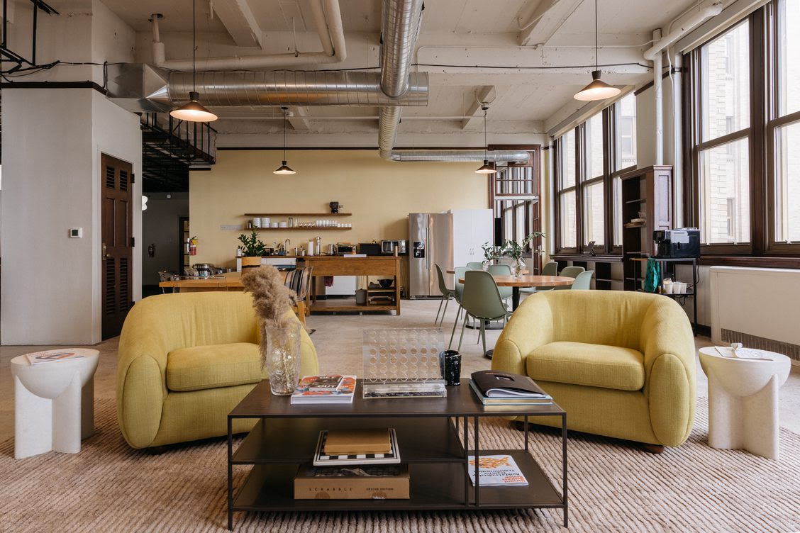 A photo of the interior of the BlackStar Project's office. There are two yellow air chairs and a coffee table. Behind is an open kitchen set-up with tables.