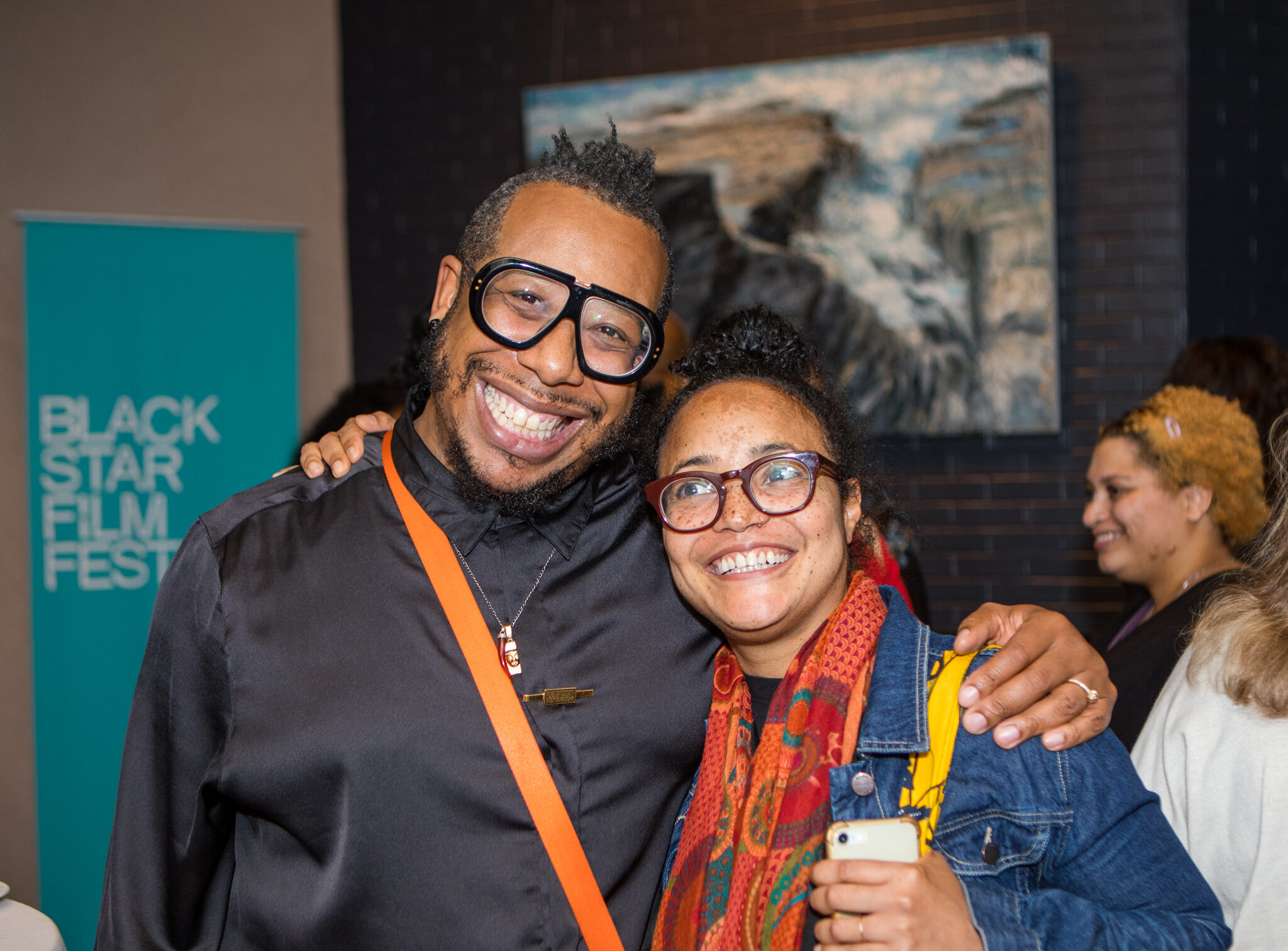 A photo of two people standing arm-in-arm and smiling.